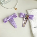 Set mit zwei lila Satin-Haarschleifen mit silbernen BB-Clips auf minimalistischem Hintergrund - Lila