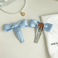 Detail von zwei hellblauen Satin-Haarspangen mit Schleife, Vorderseite und Metallclip - Blau