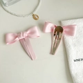 Nahaufnahme von rosa Satin-Schleifen-Haarspangen mit Metall-BB-Clip auf elegantem Stoff - Rosa
