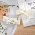 Detail of two cream double-layered bow hair clips with matching ribbon wrapped alligator clips - Beige