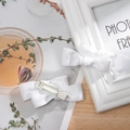 Detailed view of white satin double bow hair clips with silver alligator metal grips - White