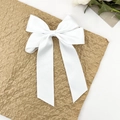 Détail d'un grand nœud à cheveux blanc élégant avec de longs rubans sur fond texturé - Blanc