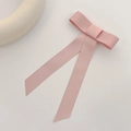 Detalle de un lazo de satén rosa pastel con cintas largas sobre un fondo minimalista - Pinza de Pelo con Lazo Rosa