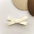 Detalle de pinza para el cabello con lazo de cinta blanco crema y tejido con textura fina - Beige