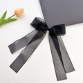 Elegant black organza bow hair clip with long ribbons on a white background with a tulip - Black Bow Hair Clip