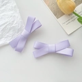 Close-up of two lavender purple bow hair clips with ribbed ribbon texture on white background - Purple