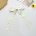 Detail of creamy white satin bow hair clip with long ribbons on a decorative background - Beige