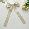 Detailed view of a champagne satin bow hair clip with elegant long flowing ribbons - Champagne