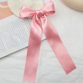 Macro detail of a large pink satin bow hair clip with silky ribbon texture on soft background - Pink