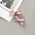 Primer plano de un par de dulces pinzas de lazo rosa hechas de tejido de grogrén de calidad - Rosa