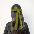 Detail of velvet bow hair clip with long ribbons worn on model's long hair - Green