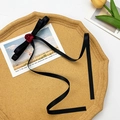 Détail du nœud élégant en soie noire avec bouton de rose rouge et longs rubans fluides - Nœud Noir Avec Rose Rouge