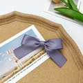 Close-up of a soft purple satin bow hair clip on a vintage postcard background - Purple