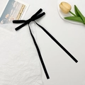Detail of long black velvet ribbon bow hair clip with flowing tassels on a white desk - Black