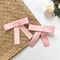 Dettaglio di due fermagli per capelli a fiocco in raso rosa con lunghi nastri eleganti - Rosa