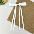 Elegant white satin bow hair clip with four long ribbons on a soft background - White