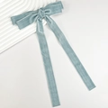Detail view of smog blue velvet bow hair clip with white piping and long ribbon ties - Blue