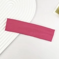Detailaufnahme des rosaroten Strickstirnbands mit Rippenstruktur auf weißem Tablett - Rosenrot