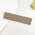 Detail eines braunen Rippstrick-Sportstirnbands auf einem weißen Tablett mit Dekokarte - Khaki