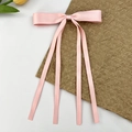 Détail de la barrette à nœud en satin rose avec de longs rubans et un éclat soyeux - Rose