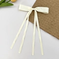 Détail d'un nœud papillon en satin crème avec de longs rubans sur un fond blanc épuré - Poche zippée
