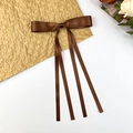 Detailed view of a brown satin bow hair clip with long ribbons on gold paper - Tan