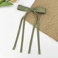 Gros plan sur une pince à cheveux en satin vert avocat avec des rubans sur fond épuré - Vert clair