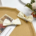 Pair of cream satin bow hair clips with silver alligator grips on cork tray - Beige
