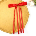 Detail of red satin bow hair clip with long ribbons on yellow display board - Red