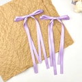 Primer plano de pinzas para el pelo con lazos de seda lavanda y cintas largas y dulces - Morado