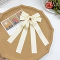 Detail of elegant cream satin bow hair clip with long ribbons on a vintage background - Beige