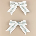 Dettaglio di due fermagli per capelli in tessuto bianco con motivi floreali blu e bordi - Bianco