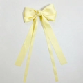 Detailed view of light yellow satin bow hair clip with long ribbons and smooth texture - Yellow