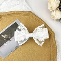 Close-up of elegant white lace bow hair clip with embroidery on a romantic tray - White
