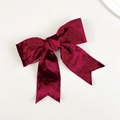 Detail of burgundy velvet bow hair clip with elegant ribbons on white surface - Burgundy