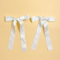 Dettaglio di due fermagli per capelli con fiocco in raso bianco e nastri lunghi eleganti - Bianco