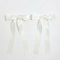 Detail of white satin ribbon bow hair clips with elegant smooth texture and long streamers - Beige