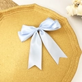Détail d'une pince à cheveux nœud en satin bleu clair avec de longs rubans sur plateau doré - Bleu