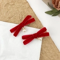 Dettaglio di due fermagli a fiocco in velluto rosso con ciondoli di perle e accenti d'oro - Rosso