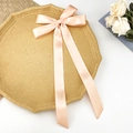 Détail de la pince à cheveux en satin rose avec de longs rubans sur support élégant - Rose Orangé