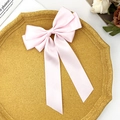 Elegant pink satin ribbon bow hair clip displayed on a minimalist yellow octagonal tray - Pink