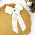 Detail of cream white satin bow hair clip with long ribbons on a decorative tray - Beige