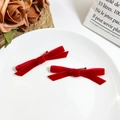 Pair of sweet red velvet bow hair clips on a white ceramic plate with vintage roses - Red