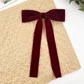 Macro detail of wine red velvet bow hair clip with long ribbons on a vintage surface - Burgundy