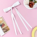 Elegant white satin bow hair clip with long ribbons on a soft pink background - White