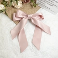 Close-up of pink satin bow hair clip with long ribbons on an aesthetic background - Pink