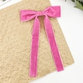 Detail of pink velvet bow hair clip with long ribbons on a textured background - Rose Red