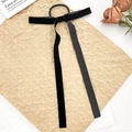 Detail eines eleganten Haargummis aus schwarzem Samt mit Schleife und langen Bändern - Schwarz