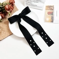 Elegant black ribbon bow hair clip with white pearl details on vintage background - Black