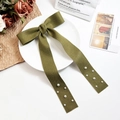 Detailed view of an olive green bow hair clip with long ribbons and small pearl accents - Green